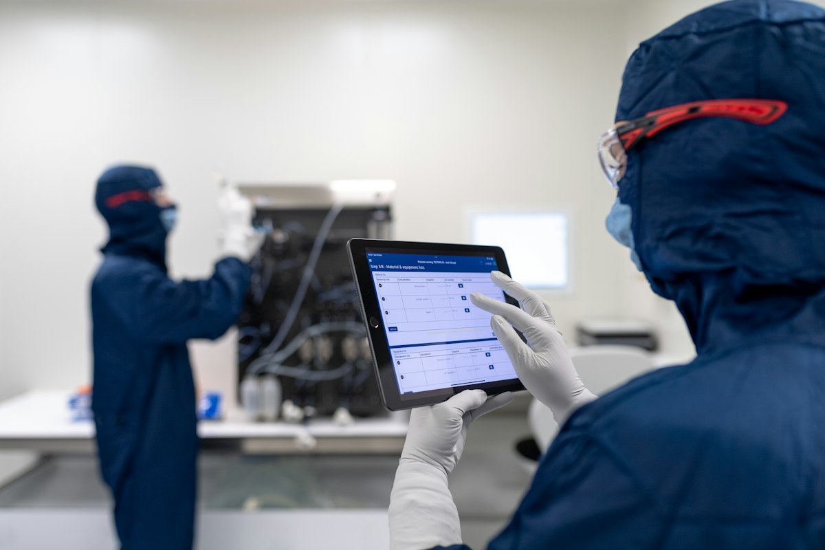 Engineer in cleanroom reviewing production data on a tablet for traceability